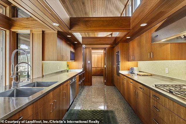 The gourmet galley kitchen (pictured) features a large gas range, stainless steel hood, thick wood beams above, granite floors and updated stainless steel appliances