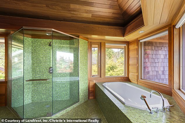 A large bathroom (pictured) features wood and sage green tiles on the floor and in the glass walk-in shower