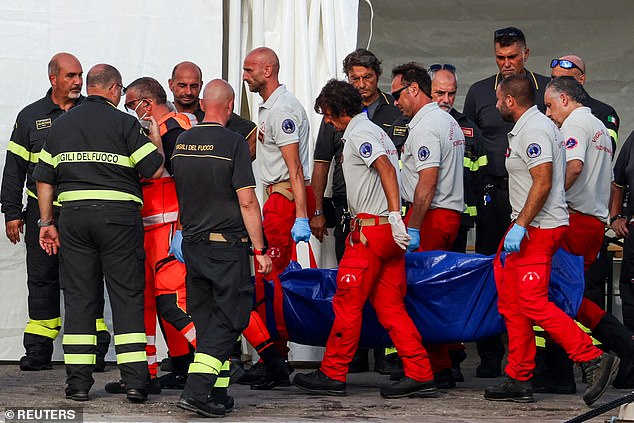 Rescue workers carry a body bag after a luxury yacht sank off the coast of Porticello, near the Sicilian city of Palermo yesterday