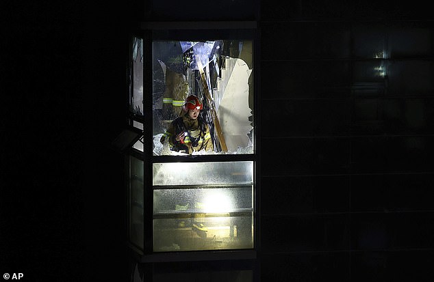 A firefighter is seen behind a broken window as he searches for missing persons in the hotel