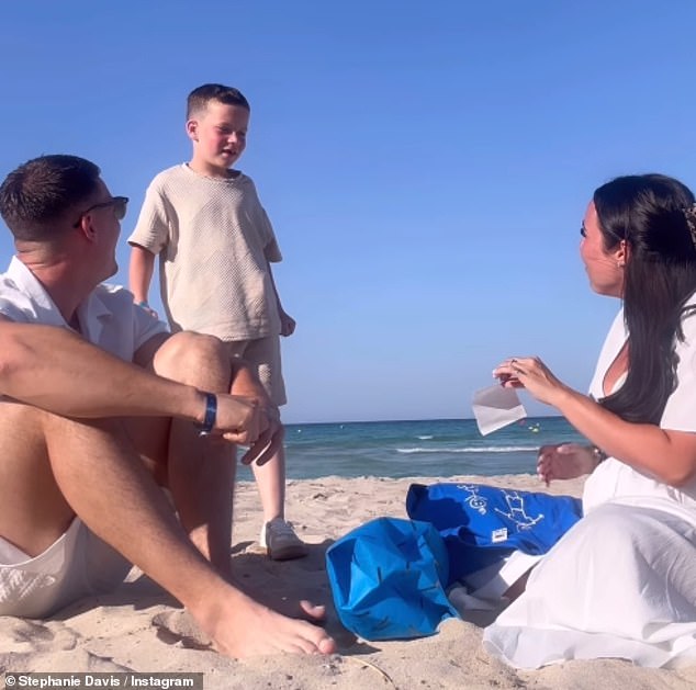 Stephanie and Joe were seen sitting on the beach and handing Caben a bag containing a T-shirt that read 'big brother' and a scanned photo