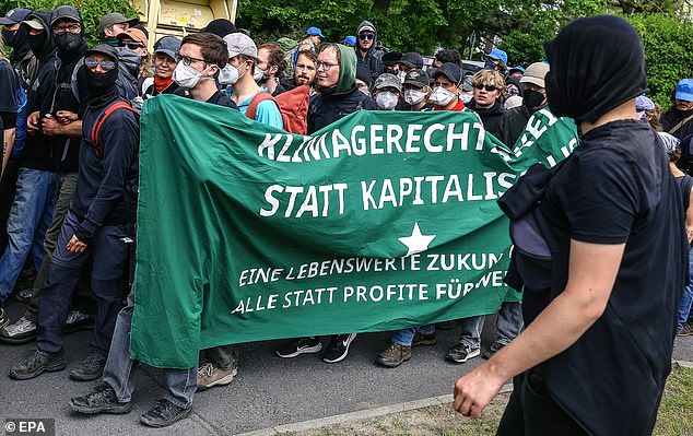 Environmental activists carry a banner as they gather during a protest against Tesla's plans to expand its Gigafactory plant, in Grünheide, near Berlin, Germany, May 10, 2024