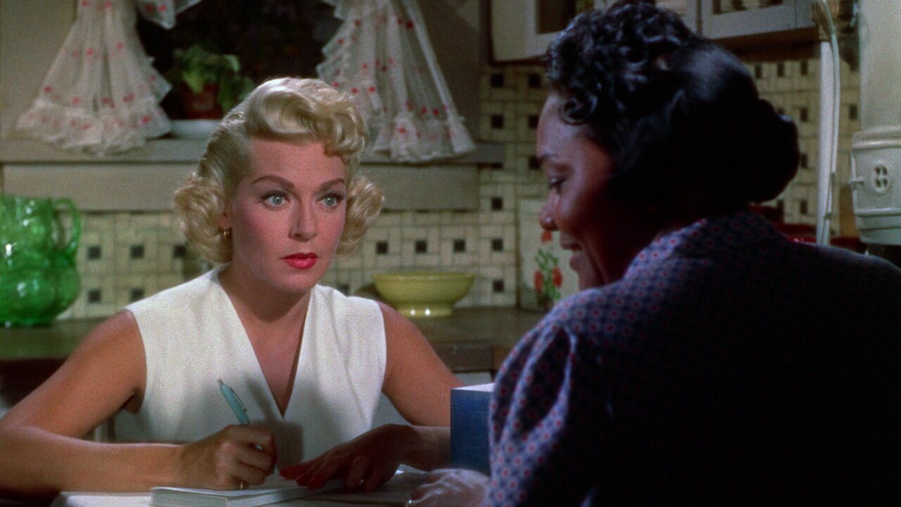 Lora (Lana Turner) and Annie (Juanita Moore) sit across from each other at a dining table in Imitation of Life (1959).