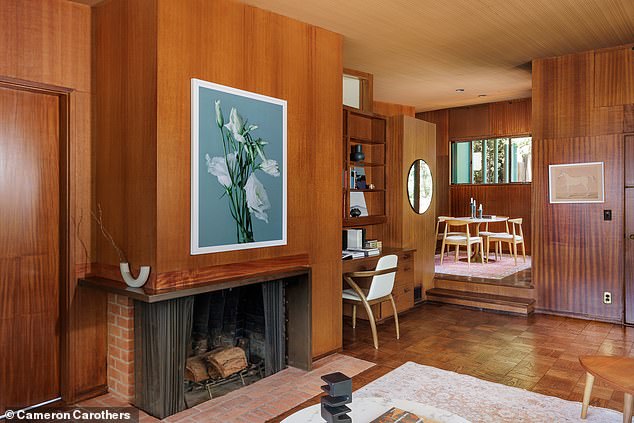 There is also a fireplace in the living room which is surrounded by more wood paneling and stone, and a small desk