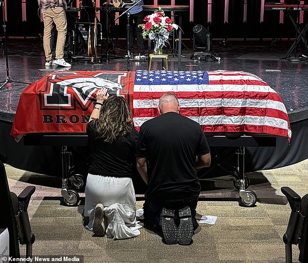 Jason and Tami Doran kneel before Zach's casket during his funeral