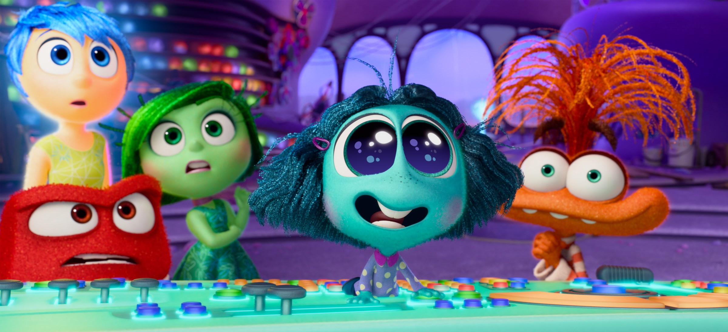 A new emotion, the aquamarine Envy (Ayo Edebiri), takes the console inside Riley's head and reacts to something off-screen with wide eyes and a bright smile in Pixar Animation Studios' Inside Out 2