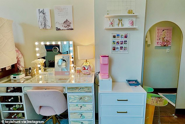 Ava's dorm room featured a silver and white vanity with a pink chair, a nightstand, and shelves. On the vanity was a shiny lamp and a mirror with small lights on the edge