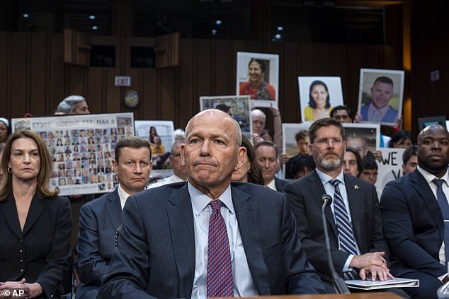 Boeing CEO Dave Calhoun takes his seat to testify before the Senate Committee on Homeland Security and Governmental Affairs, with protesters in the audience