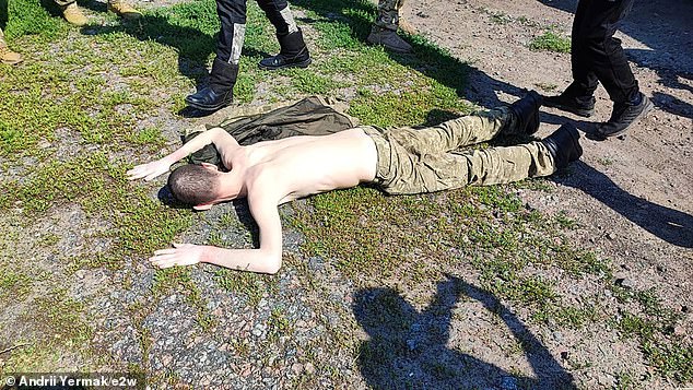 A Ukrainian prisoner of war lies on the ground after being released from captivity in Russia