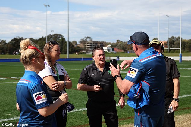 Officials from both teams and an NRL representative (in black uniform, centre) are pictured talking during the delay caused by the lack of medical staff.