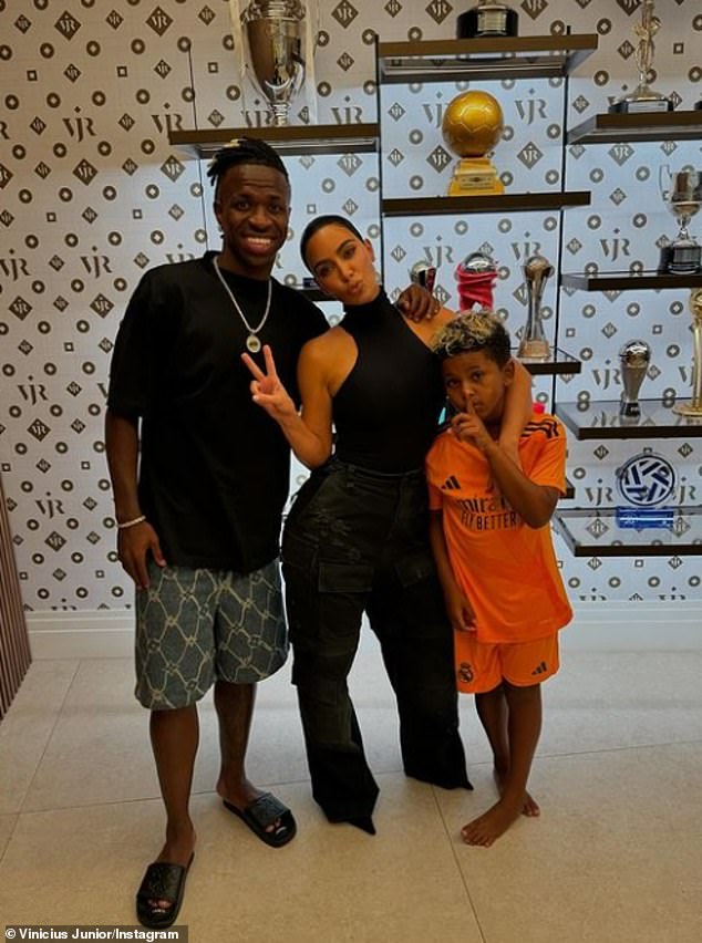 The influencer looked amazing in a black bodysuit and cargo jeans as she posed with Saint and Vinicius Jr for an Instagram snap