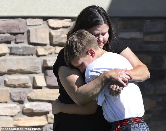 Neighbors hug after a 5-year-old boy accidentally shot himself with a gun he found in his parents' bedroom in Santaquin, Utah