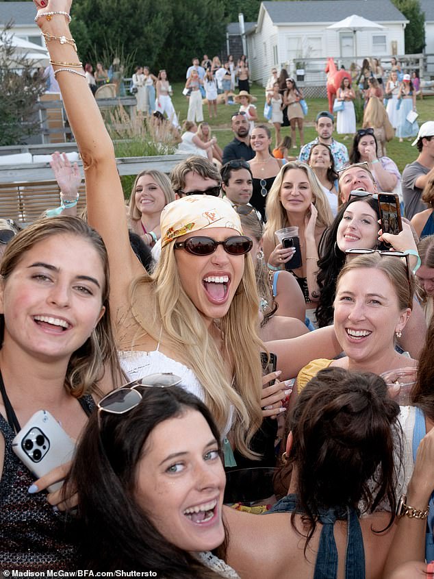 She was spotted with a drink in her red manicured hand at the outdoor party on Saturday