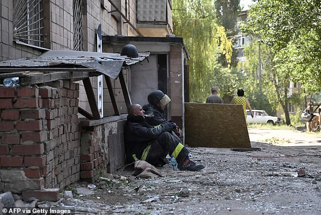 Ukrainian rescuers take a break during a search and rescue operation among the rubble of a destroyed hotel after an attack in the city of Kramatorsk, Donetsk region on Sunday