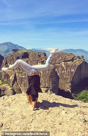 Here she performs a gymnastic move near what appears to be the edge of a mountain