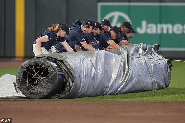 Ground crew members roll out the tarp in Minneapolis at the start of the storm