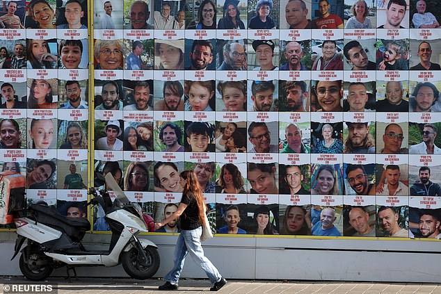 A person walks past a wall with posters of hostages, most of whom were abducted during the deadly Hamas attack on October 7 in Tel Aviv, Israel