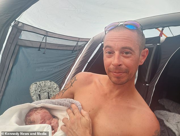 Stuart Doyle is photographed holding his baby daughter after giving birth to her in a tent