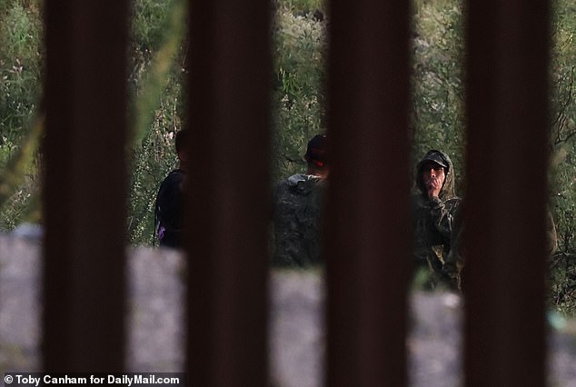 They were accompanied by a group of migrants who appeared to have set up a cross near the huge hole in the wall