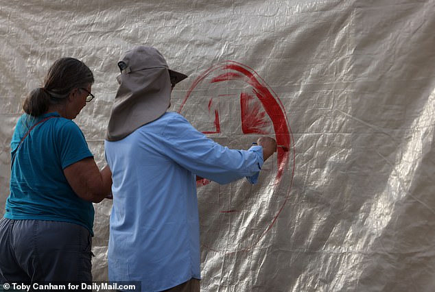 Aid workers paint a tent with a red cross at the gap in the border wall east of Sasabe