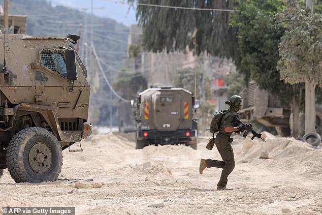 An Israeli soldier is seen near armored vehicles during a raid on the Nur Shams refugee camp