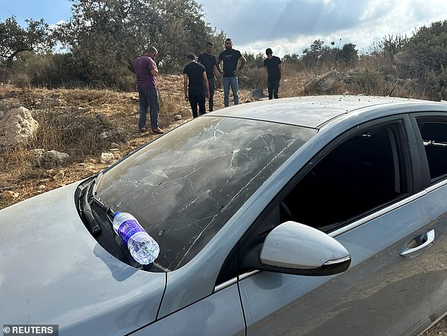 Palestinians assess the damage to a car during a military operation by Israeli forces near Jenin in the Israeli-occupied West Bank