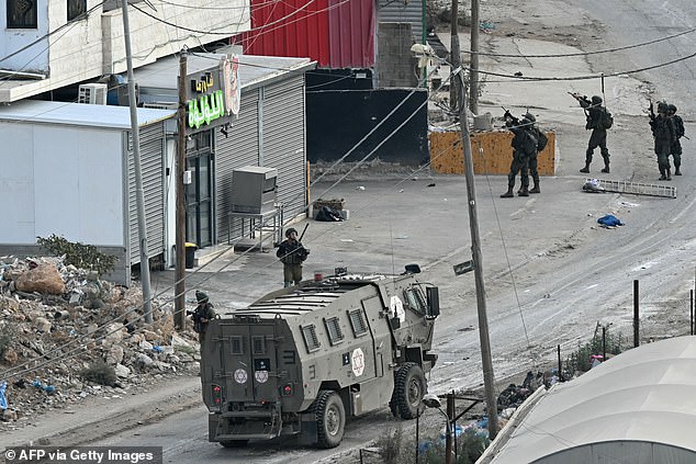 Israeli soldiers walk through a street during a raid on the al-Faraa camp near the town of Tubas