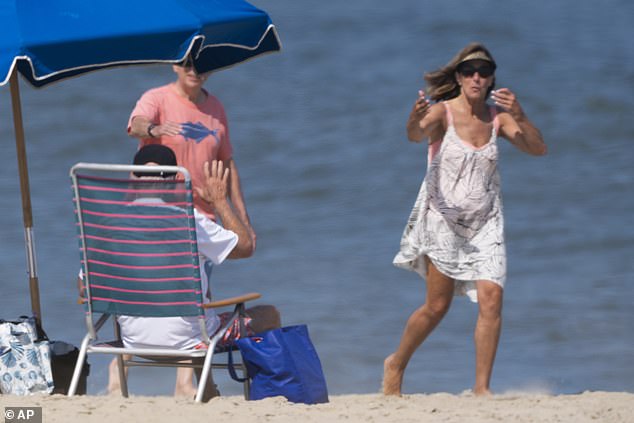 Passersby wave to President Biden as he sits on the beach