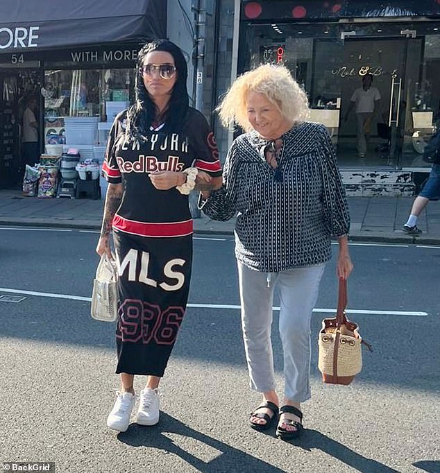 For the outing, Katie turned heads in a black, sporty maxi dress by Red Bull, which she paired with white trainers and a matching handbag.