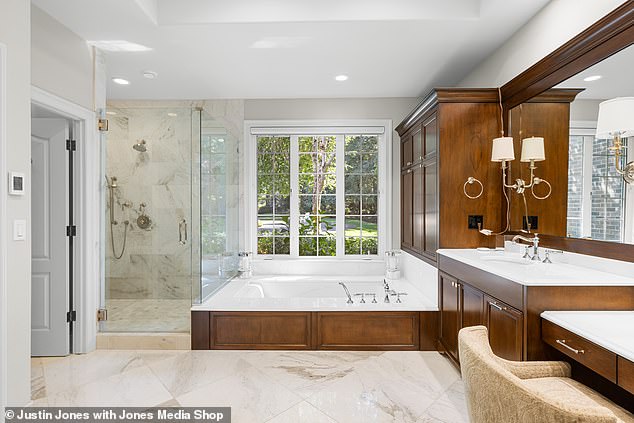 It opens into a private bathroom with a large soaking tub, glass shower and double sinks