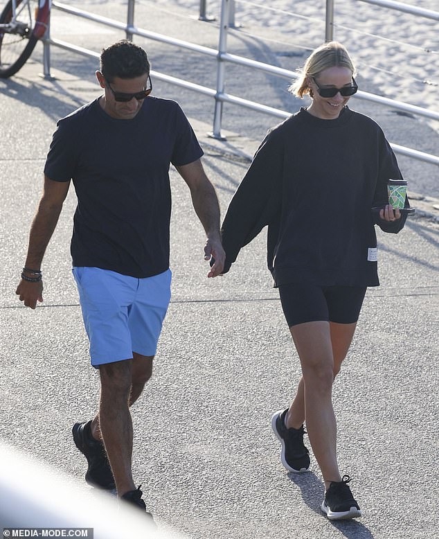 The couple looked comfortable in each other's company as they laughed and smiled together as they walked along the beach