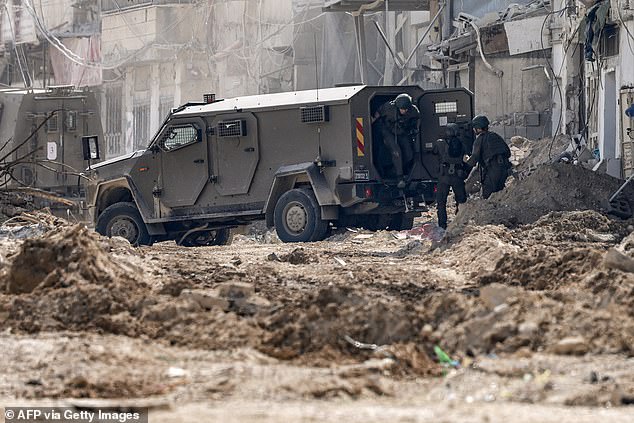 Israeli soldiers step out of an armored vehicle as they take up position during an army operation in Tulkarm