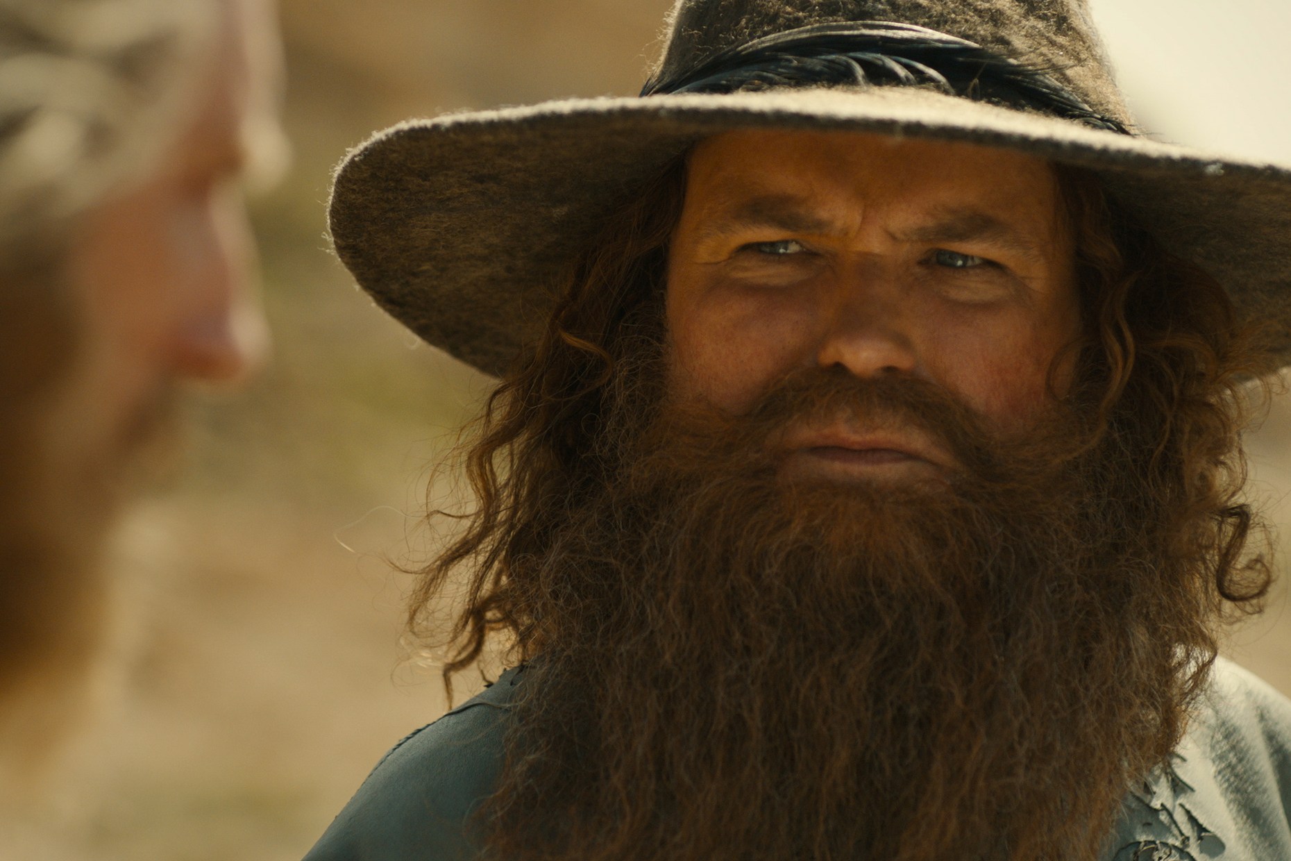 Tom Bombadil in a big hat and beard leers at The Stranger in The Lord of the Rings: Rings of Power season 2