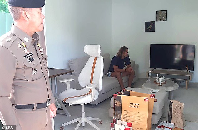 A handout photo provided by the Royal Thai Police shows Spanish chef Bronchalo sitting next to evidence and a police officer after he was arrested for murder and dismembering the body of a Colombian man.