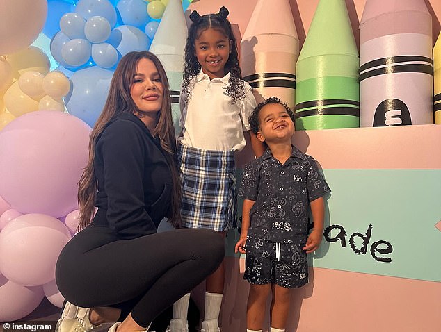 Khloe sweetly embraced her daughter, who was holding the family cat, as they all posed in front of a sign that read 