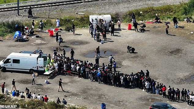 A large group of migrants receive help from charity workers in northern France