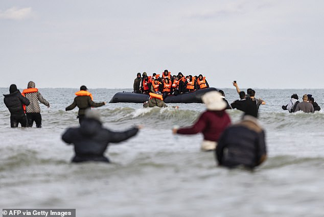 Migrants walk through water as they desperately try to board a smuggling boat on the northern coast of France (file photo)