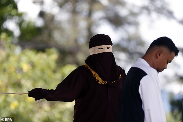 An executioner, known as an 'algojo', carries out a public caning in the town of Jantho, Aceh