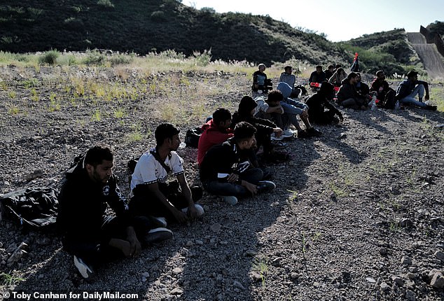 A group of men from Nepal and Bangladesh sit on a dirt road near the U.S.-Mexico border, waiting for a ride from federal agents. These men were eventually found by authorities and would not be considered an escape route