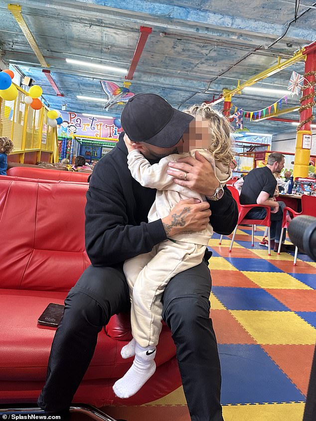 The Manchester City star pulls his son onto his lap for a hug