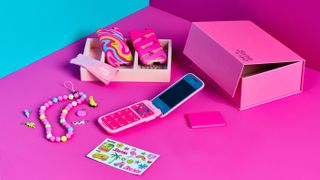 The Barbie Flip Phone and accessories on a pink table