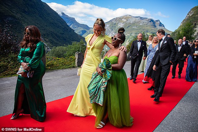 Wedding guests in glamorous dresses as they parade down the red carpet