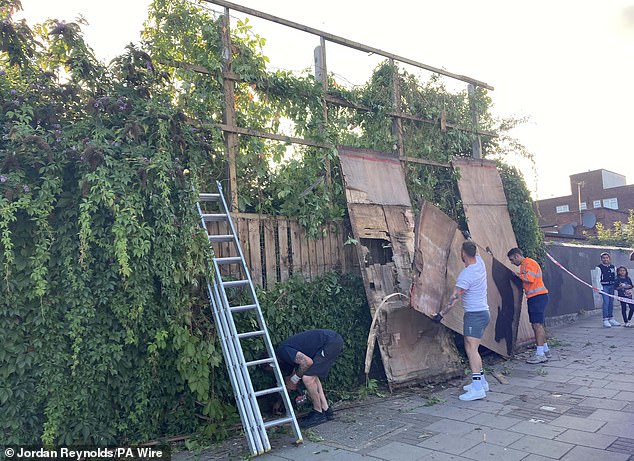 Contractors remove Banksy's latest artwork - a silhouette of a cat - from a billboard in Cricklewood