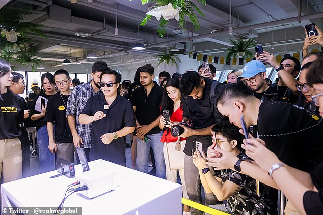 The 'Pocket Cannon' charger is paired with a new battery design that significantly reduces charging speeds. Pictured: Tech fans jostle to take photos of the new charger and battery