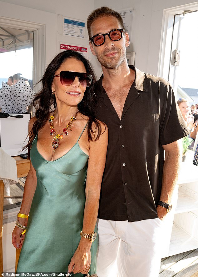 She showed off a fuller bust in the slinky, low-cut piece and added a striking yellow and red floral necklace; pictured with Simon Huck