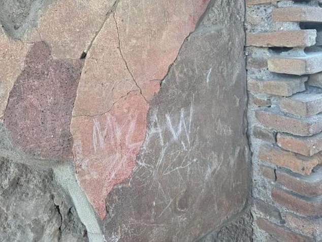 The graffiti that the tourist actually etched on the wall of the House of the Vestal Virgins in Pompeii, showing his and his daughters' initials, JW, LMW and MW, alongside MLAW and the date 07/08/24