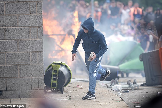 This afternoon, violent protesters wearing balaclavas and carrying St George's flags clashed with officers trying to protect the Holiday Inn Express in Rotherham, South Yorkshire, setting fire to bins and furniture.