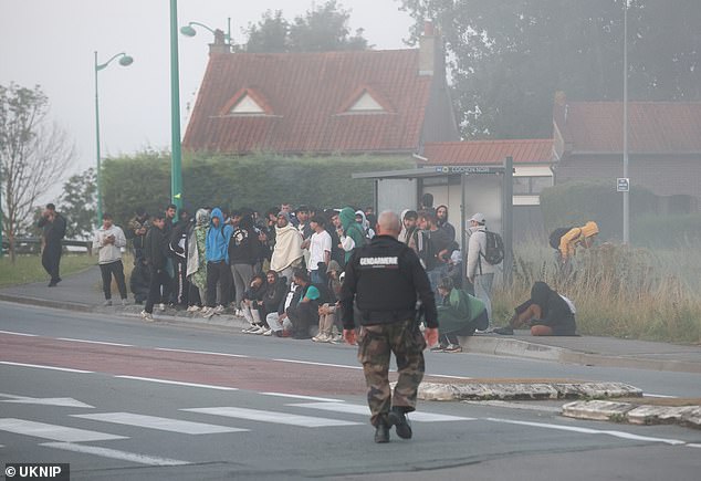 A gendarme is seen approaching a group of migrants in the town of Gravelines, near Dunkirk