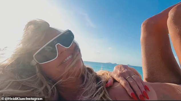 In a selfie video, Klum can be seen leaning on her husband on the sand, covering her breasts with one hand while recording the clip with the other