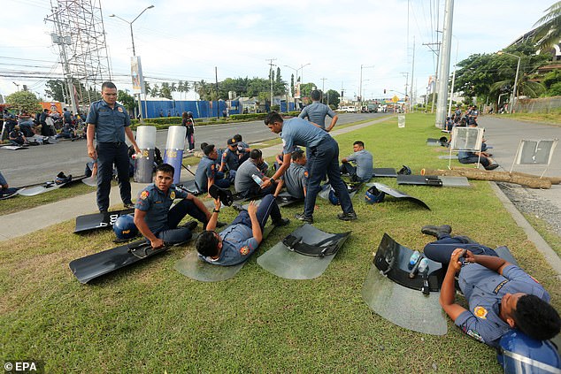 Anti-riot police rest in front of the Kingdom of Jesus Christ (KOJC) complex in Davao City